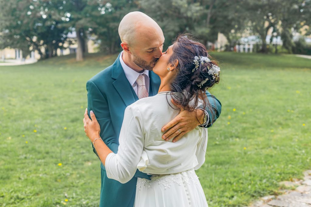 les deux mariés s'embrassent dans le parc du domaine de leur mariage