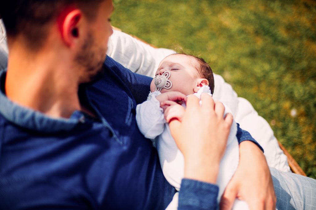 Un papa et son bébé nouveau né à son domicile assis sur le transat